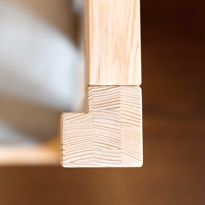 A close-up of a square corner joint of a wooden piece, with the wood grain visible.