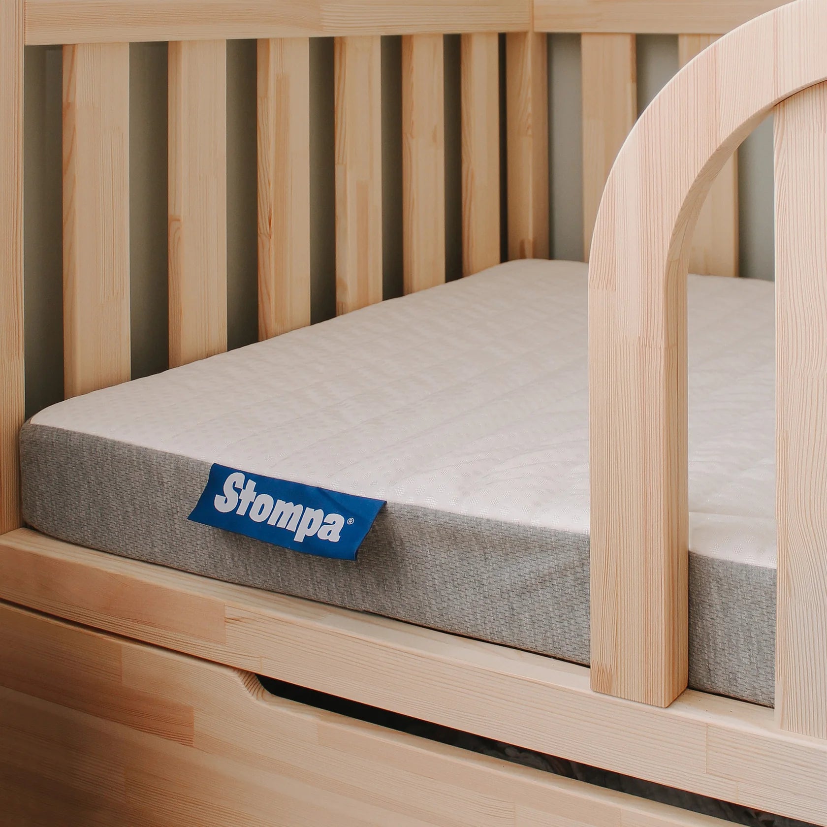 Wooden bed with a gray mattress and Stompa logo